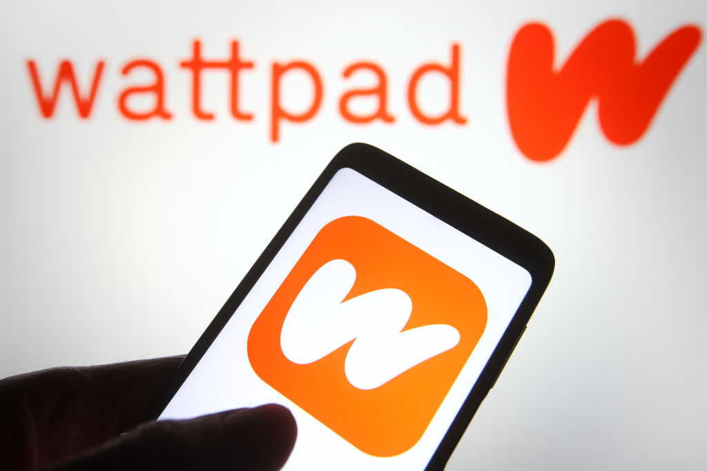 In this photo illustration a Wattpad logo is seen on a smartphone and a pc screen. 