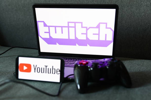 Twitch logo displayed on a laptop screen, YouTube logo displayed on a phone screen and a gamepad are seen in this illustration photo taken in Krakow, Poland on August 23, 2022. 