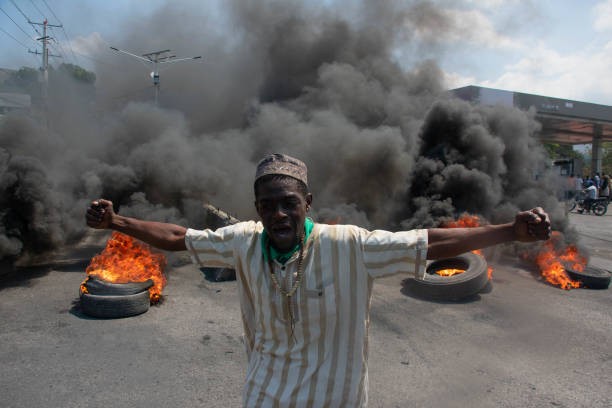 TOPSHOT - A protester reacts while tires burn in the street during a demonstration following the resignation of its Prime Minister Ariel Henry, in Port-au-Prince, Haiti, on March 12, 2024. A political transition deal in Haiti marks a key step forward for the violence-ravaged country but far more needs to be done, with some experts warning the situation could deteriorate further.