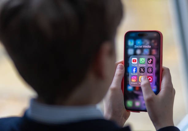 BATH, UNITED KINGDOM - FEBRUARY 25: In this photo illustration a a 12-year-old school boy looks at a iPhone screen A 12-year-old boy looks at an iPhone screen showing various social media apps including TikTok, Facebook and X on February 25, 2024 in Bath, England.