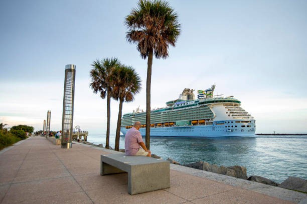 A man watches as Royal Caribbean International's Freedom of the Seas cruise ship sets off down Government Cut past Miami's South Pointe Park on a simulated voyage from PortMiami on June 20, 2021. 