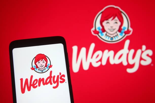 UKRAINE - 2021/05/10: In this photo illustration the Wendy's logo of an US international fast food restaurant chain is seen on a smartphone and a pc screen. 