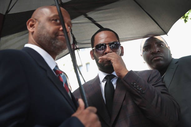 CHICAGO, ILLINOIS - JUNE 26: R&B singer R. Kelly covers his mouth as he speaks to members of his entourage as he leaves the Leighton Criminal Courts Building following a hearing on June 26, 2019 in Chicago, Illinois.